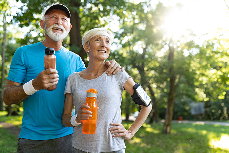 Older couple walking outside while holding water bottles