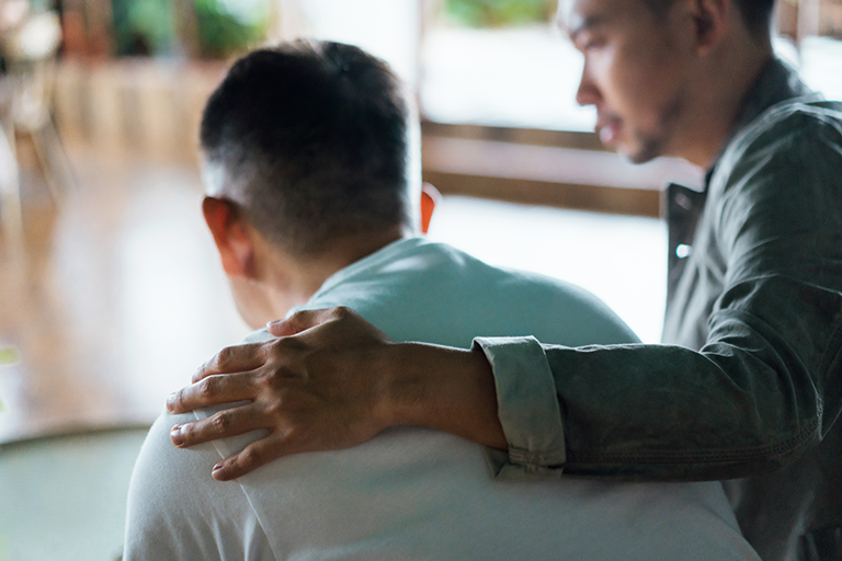A younger man with his hand over the shoulder of an older man who is in distress.