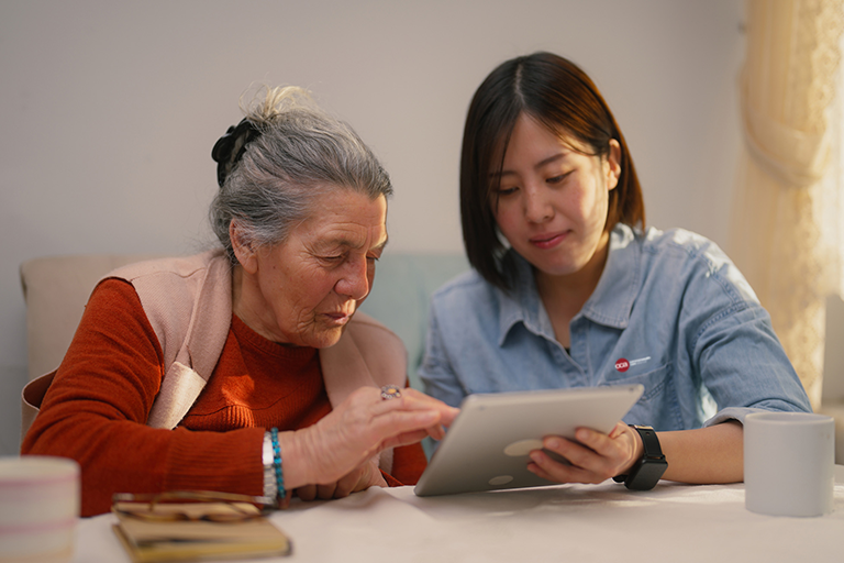CCA care partner and CCA member meeting and looking at information on an ipad.